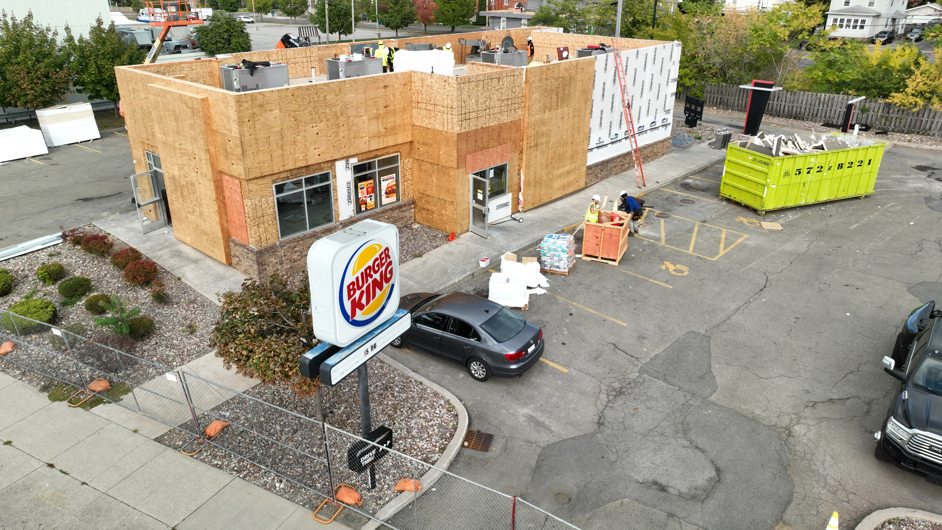 Commercial building stripped to bare sheathing during a full exterior reconstruction, seen from a drone